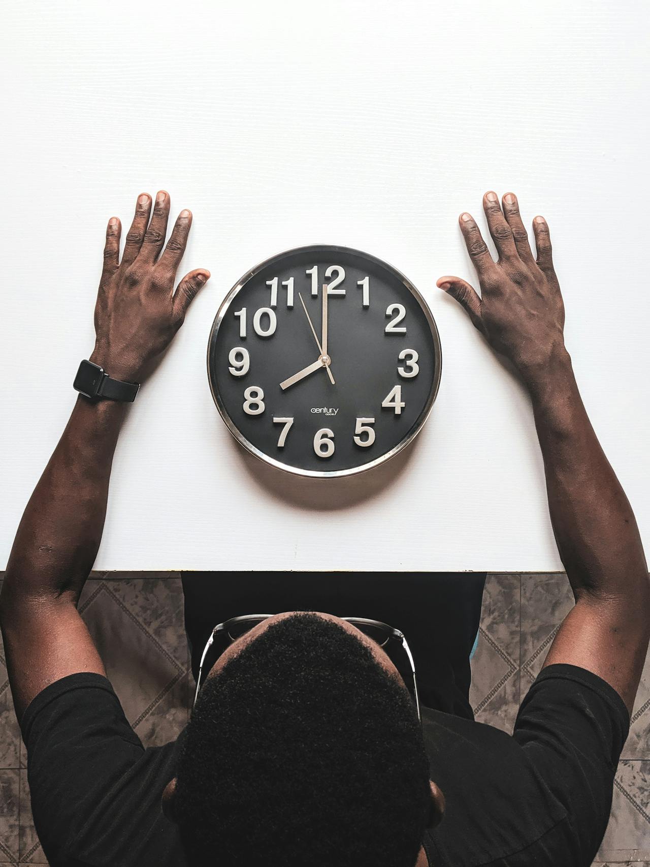 Hombre sentado observando un reloj analógico