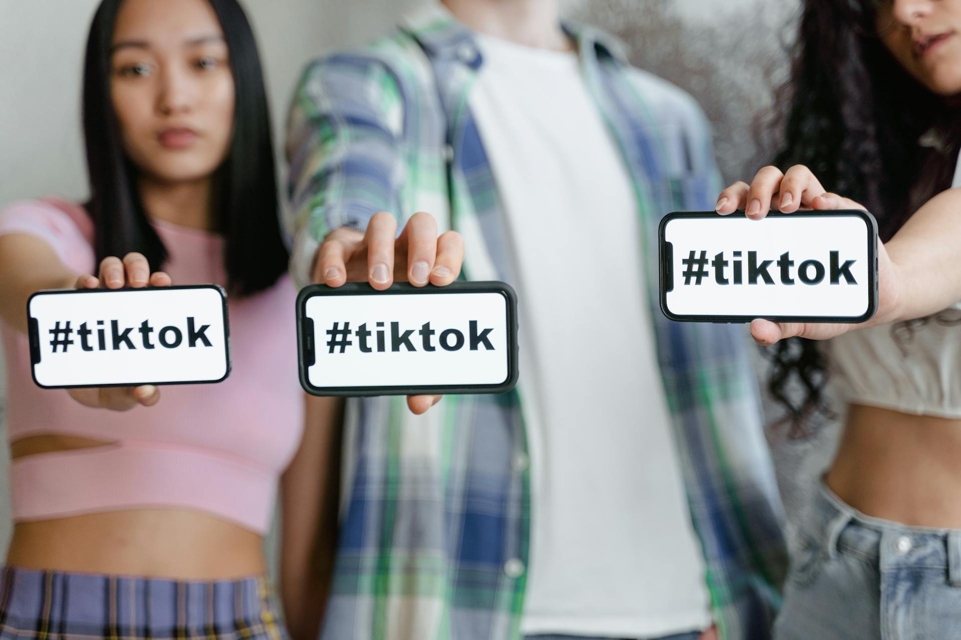 imagen de tres personas mostrando su teléfono móvil en el que se lee la palabra Tiktok